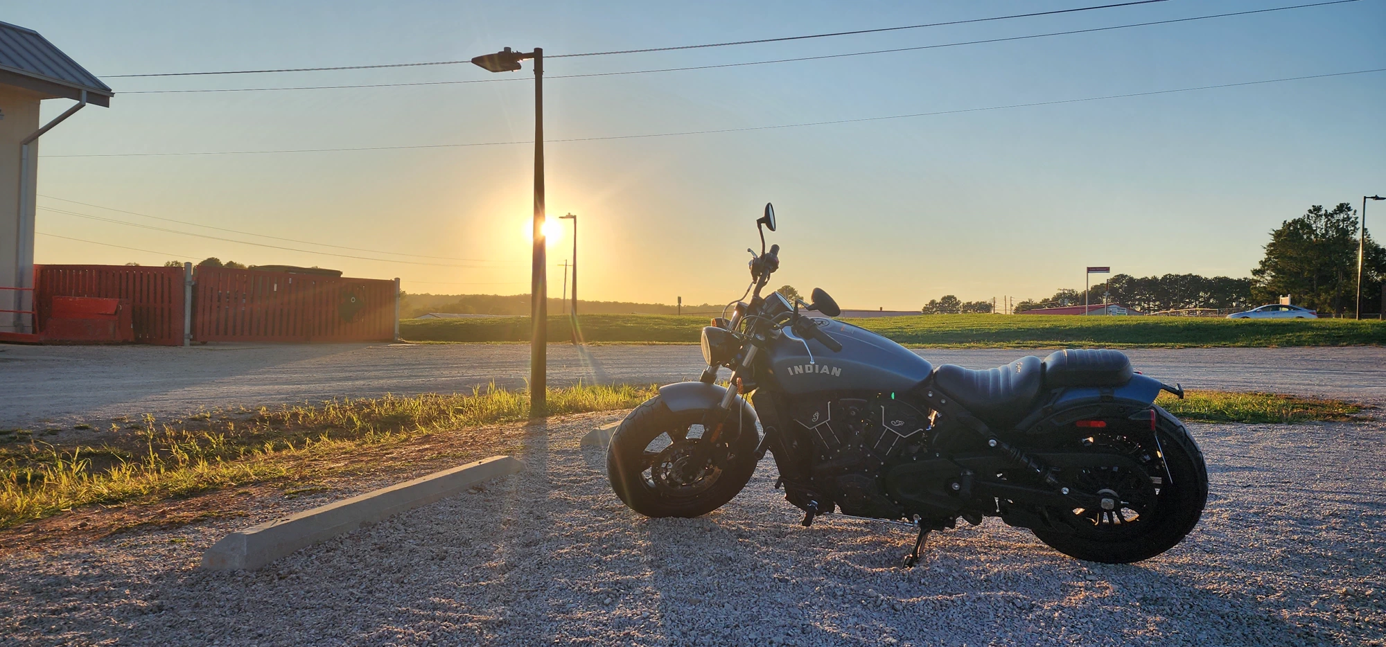 A black Indian Scout motorcycle parked outdoors at sunset.